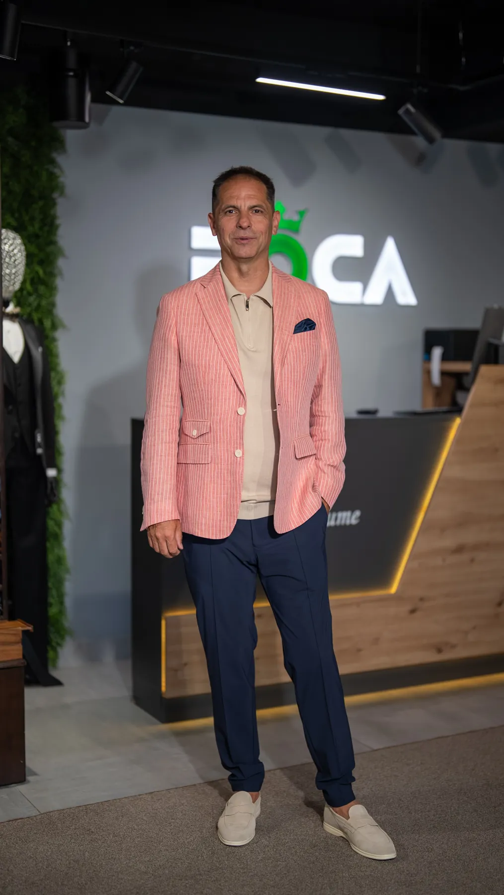 Sacou somon cu dungi și polo bej, în fața recepției ROCA
